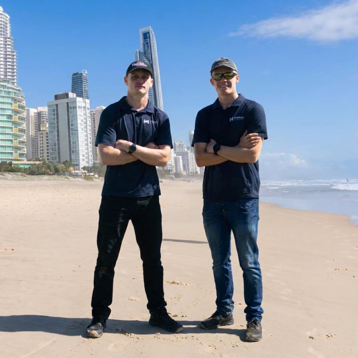 Shaun and Justin, the two brothers behind Moral Service, on the beach with the Surfers Paradise skyline behind them