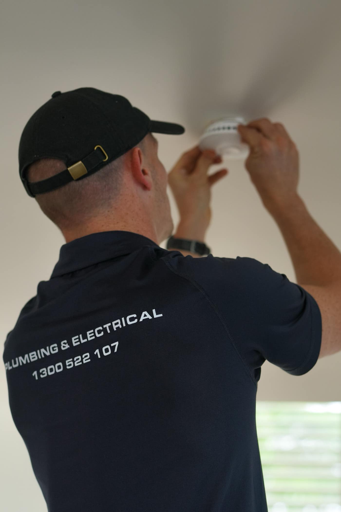 A Moral Service electrician fitting a smoke alarm to the ceiling
