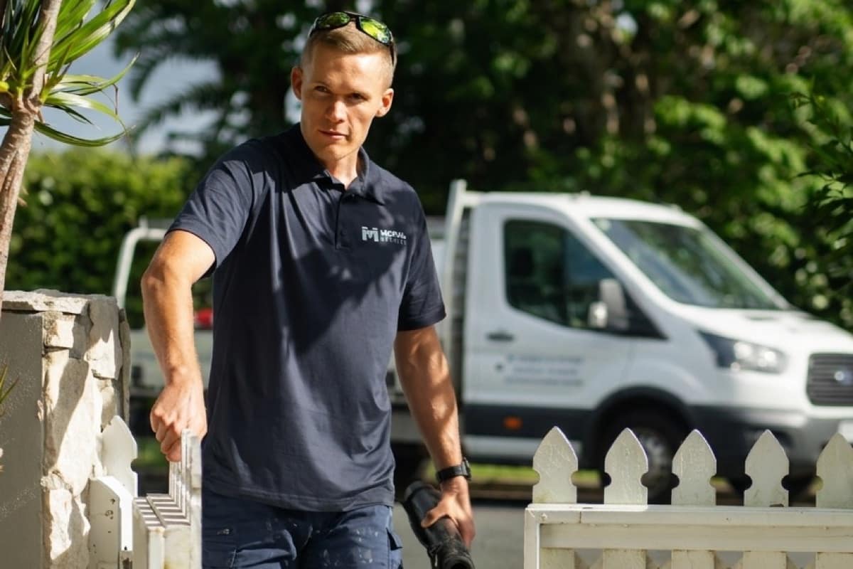 A Moral Service plumber arriving at a Gold Coast home, tool bag in hand, through the front gate