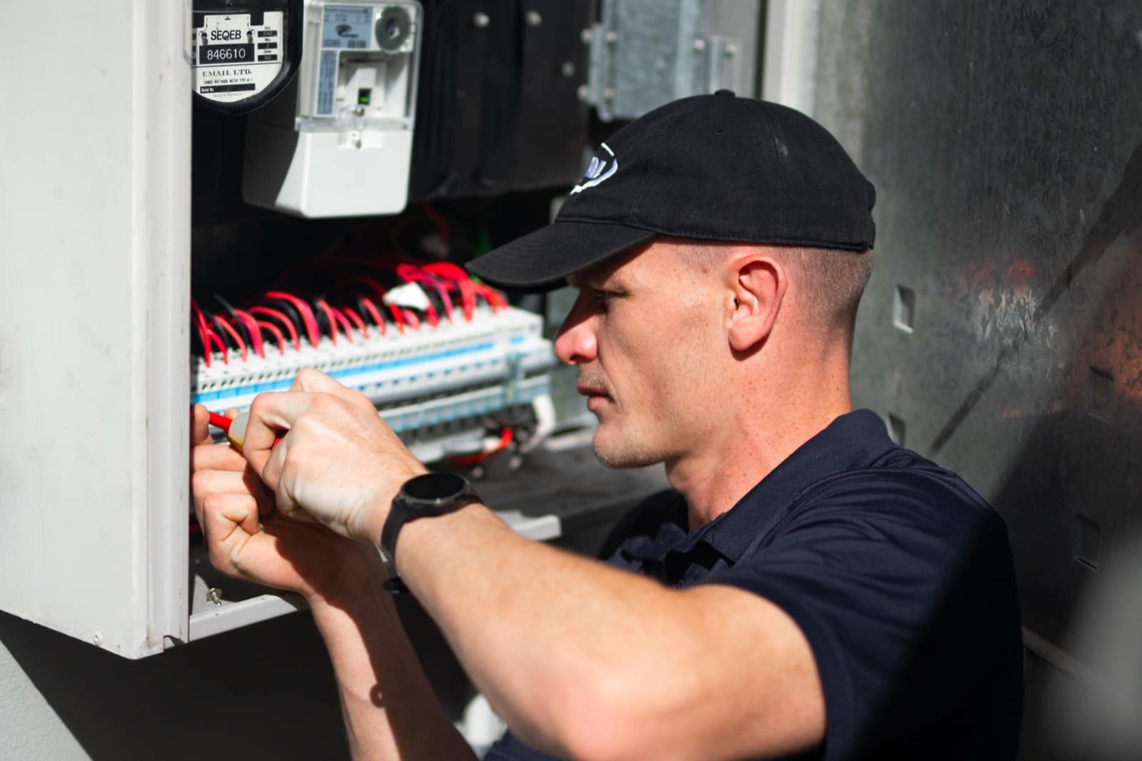 A Moral Service electrician working on a home switchboard with an insulated screwdriver